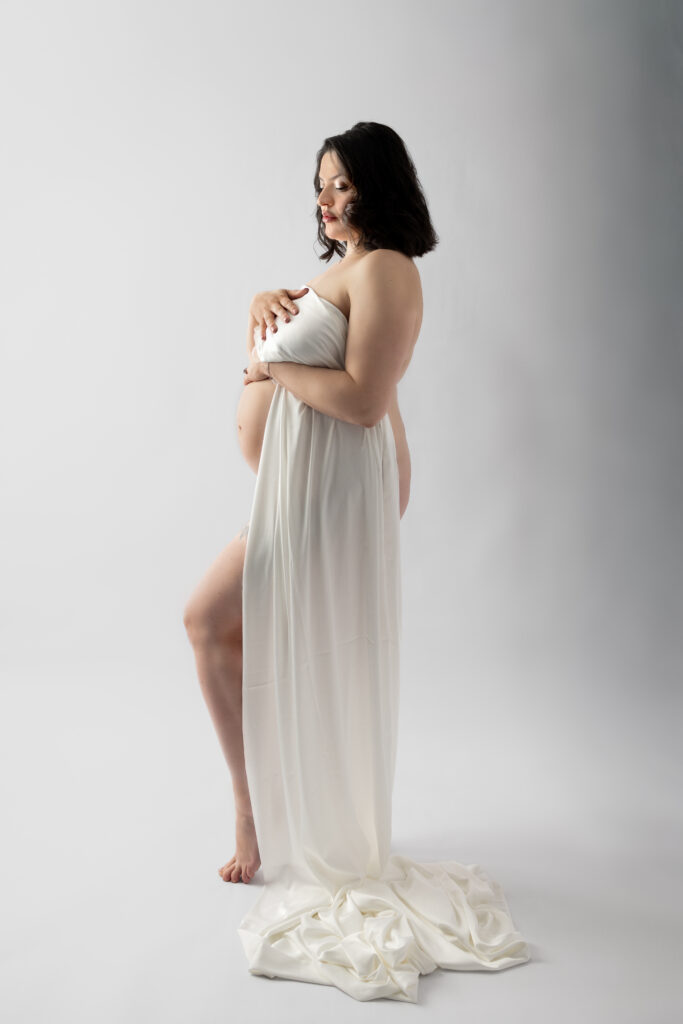 Artistic maternity silhouette with flowing white fabric highlighting a growing baby bump.