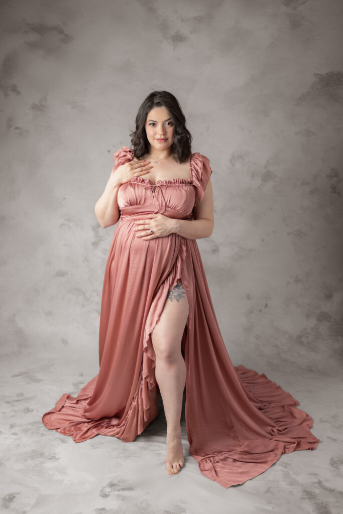Expectant mother in dusty rose gown posing during a maternity portrait session.