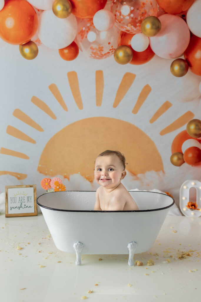Birthday girl sits in a white clawfoot tub during cake smash cleanup in Bergen County.