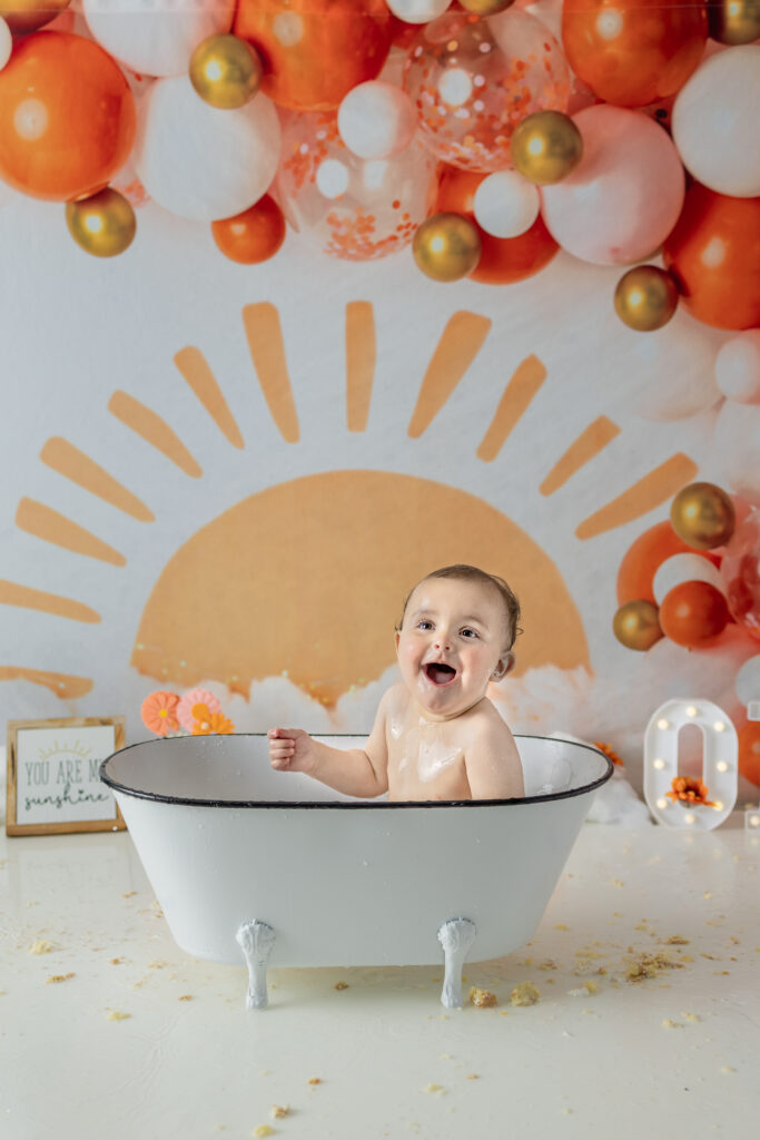 One-year-old girl enjoys a bubble bath after her first birthday cake smash session.