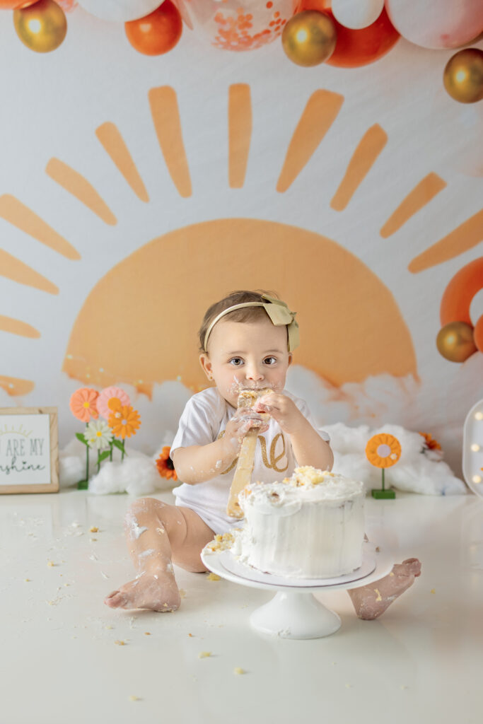 Birthday girl leans forward to taste her cake during a Bergen County first birthday session.