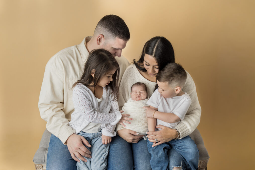 Parents and siblings admire their sleeping newborn during a cozy family portrait in Jersey City.