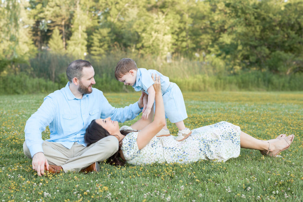 Parents play with their toddler in a flower-filled field during a Bergen County, NJ family session.