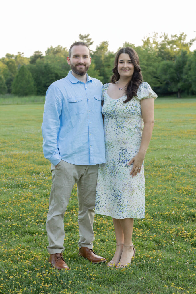 Parents stand together in a summer field during an outdoor Bergen County, NJ family session.