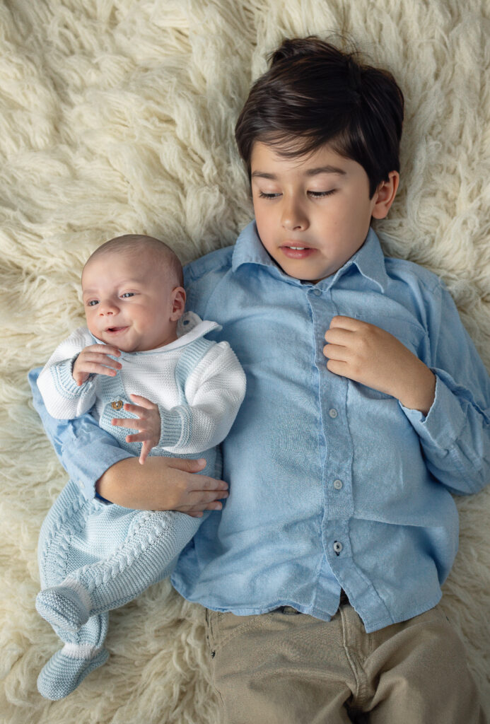Bergen County, NJ newborn photographer captures an older brother gently holding his baby sibling during a sibling portrait.