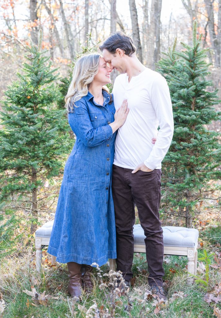 Couple shares a sweet moment among Christmas trees during their holiday mini session in West Milford, New Jersey.